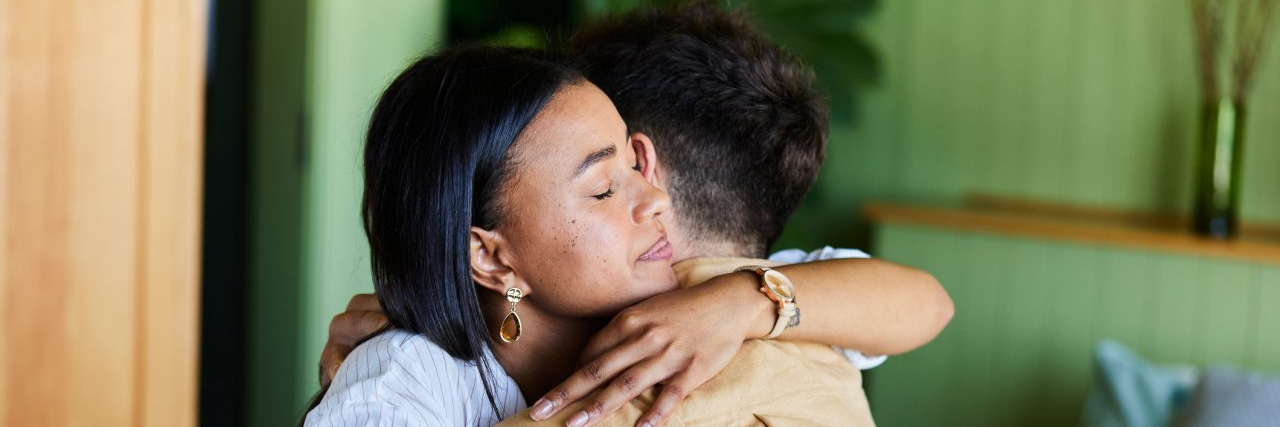 How Family and Friends Shape Recovery Young woman consoling her husband with a hug while sitting together on their bed at home