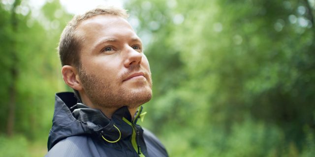 Man looking at the green leaves and trees around him