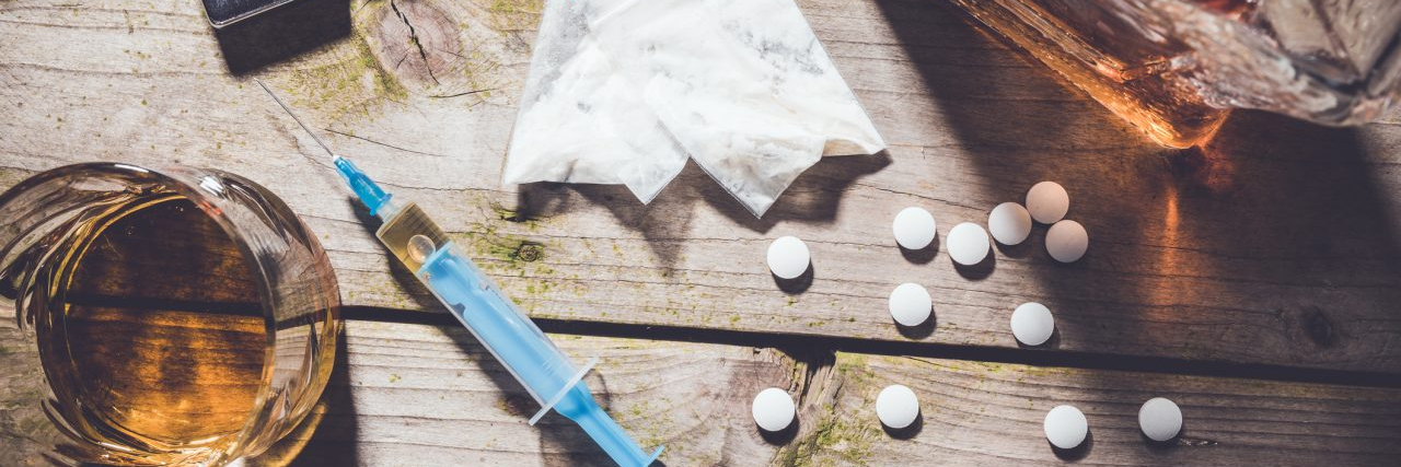 What Is Substance Use Disorder? Overhead shot of hard drugs and alcohol on wooden table. Addiction concept