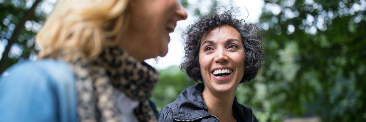 How Having Epilepsy Impacts Daily Life Woman looking at friend and smiling in forest.