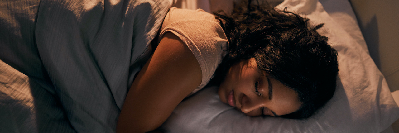 Strategies for Better Sleep With Migraine High angle shot of woman of color sleeping in bed at night