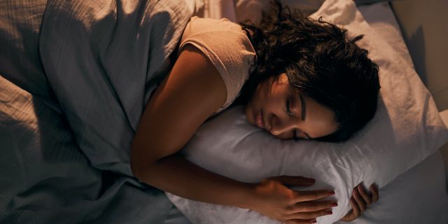 High angle shot of woman of color sleeping in bed at night