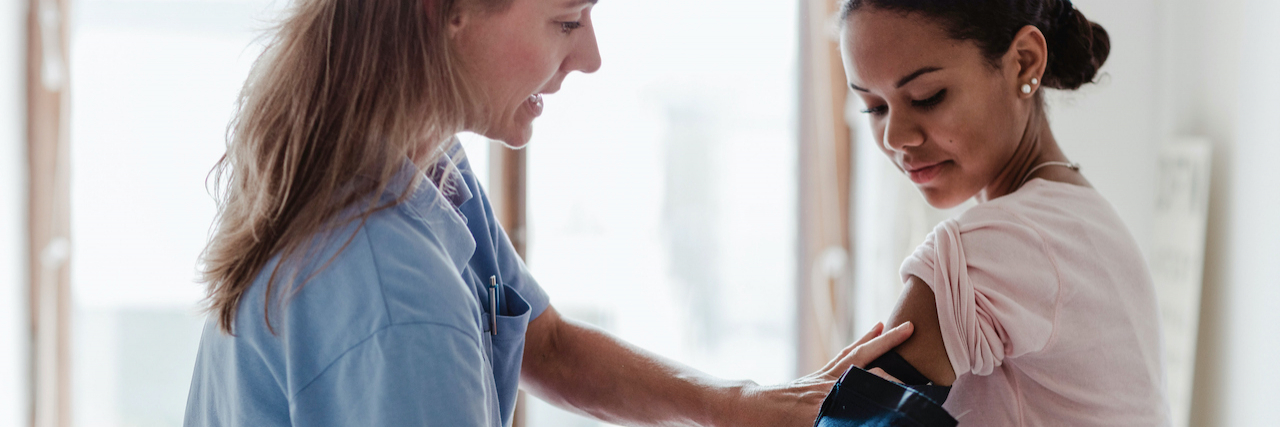 Migraine vs. Stroke: Differences and Warning Signs Burse checking patient's blood pressure in exam room