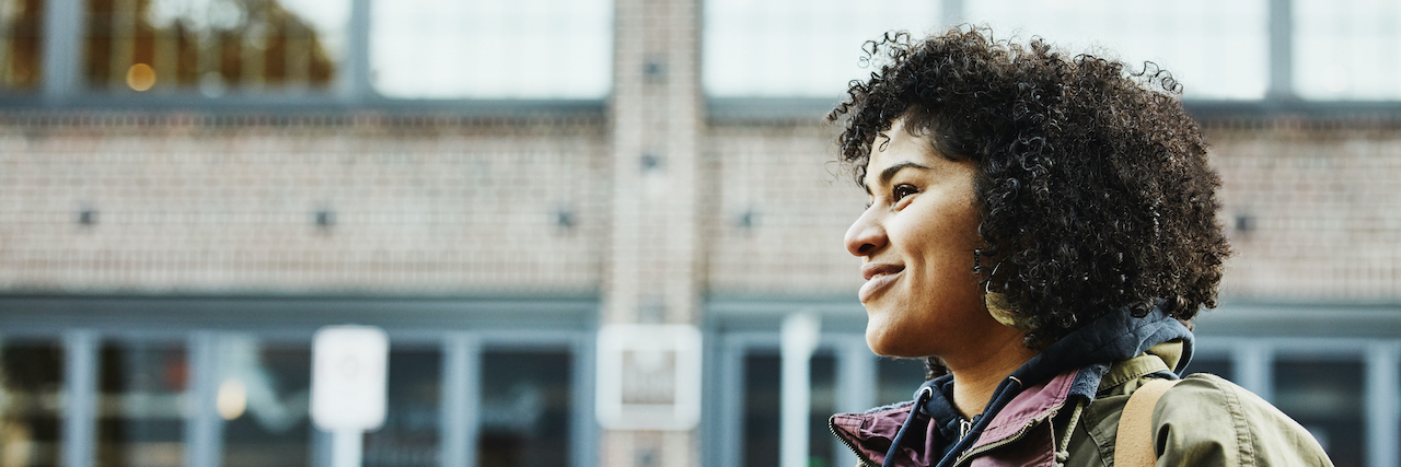 How to Fight Apathy and Find Motivation With Depression Portrait of woman of color smiling and walking on city street
