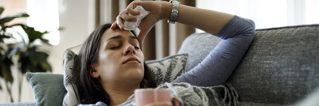 Can Depression Make You Sick? Sick woman lying on couch holding a tissue