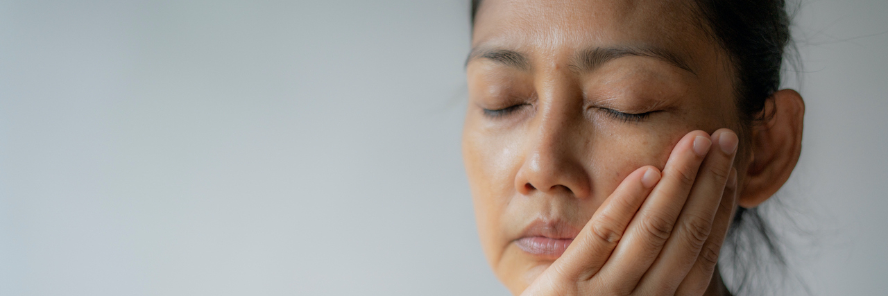 The Connection Between TMJ and Migraine Woman holding her jaw