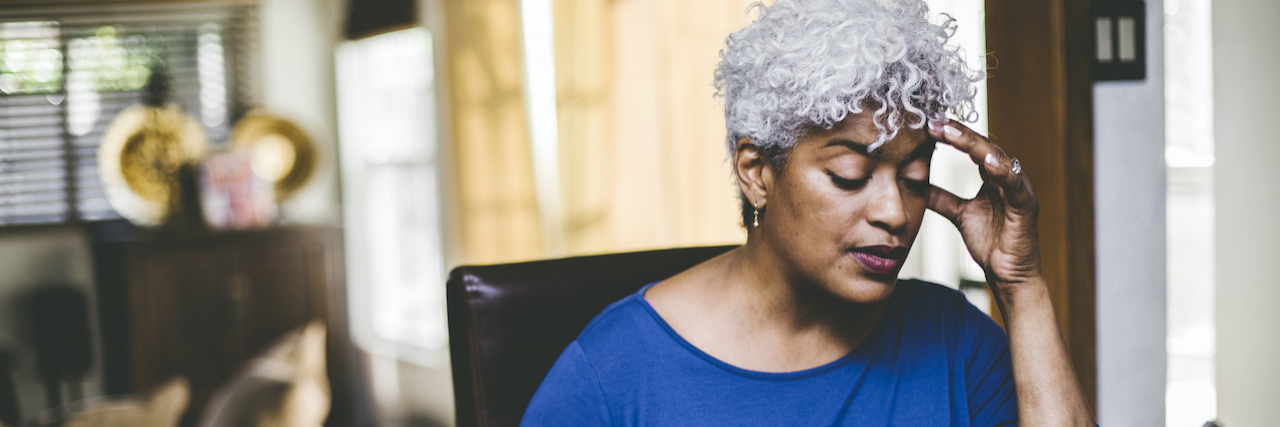 Why Do I Keep Getting Migraine Attacks? Black woman with white hair holding her head and a coffee mug