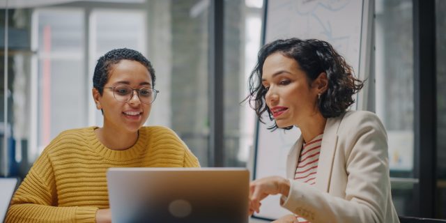 Seeking Accommodations for Epilepsy as a Disability in the Workplace Two women of color at work having a discussion by a laptop