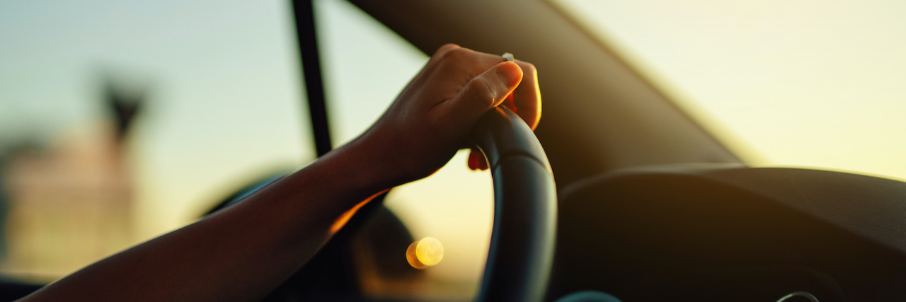 Close up of hand holding steering wheel in a car during a drive