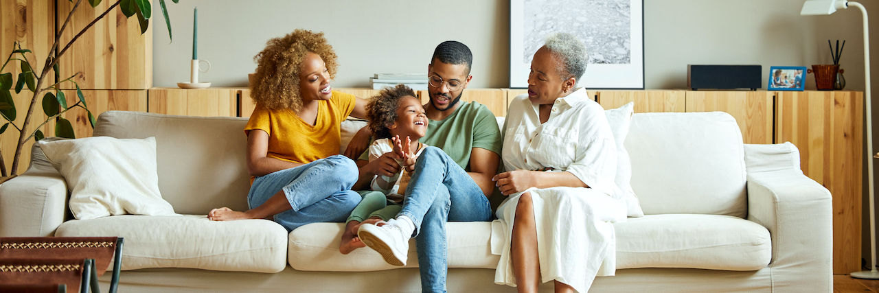 The Role of Genetics in Migraine Cheerful boy with parents and grandmother on sofa.
