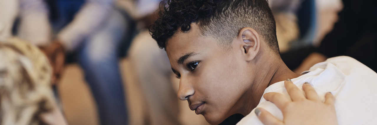 Signs of Depression in Teens: What to Look For Teenage boy of color with someone's hand on his shoulder in support