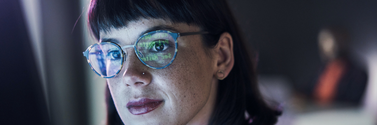 Business woman with reflection of computer on her blue light glasses.