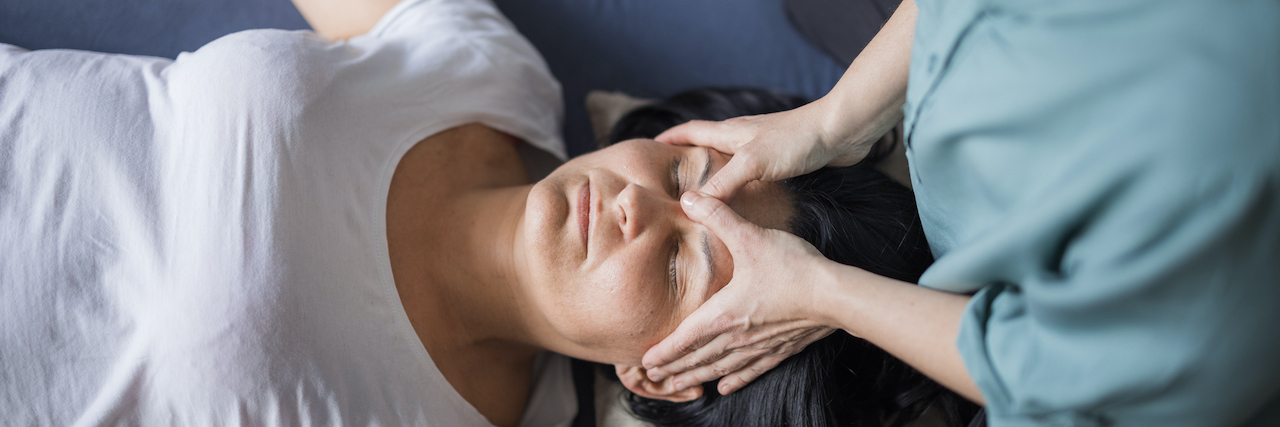 Woman receiving massage on face between her eyes