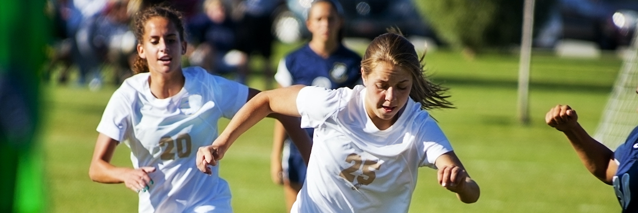 Female soccer players dribbling the ball on the field