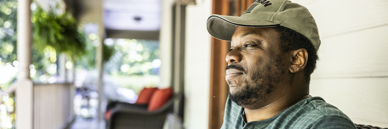 What to Know About Qualifying for VA Disability Benefits With Migraine   Portrait of Black U.S. military veteran on front porch of suburban home