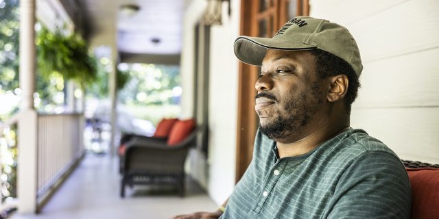 What to Know About Qualifying for VA Disability Benefits With Migraine   Portrait of Black U.S. military veteran on front porch of suburban home