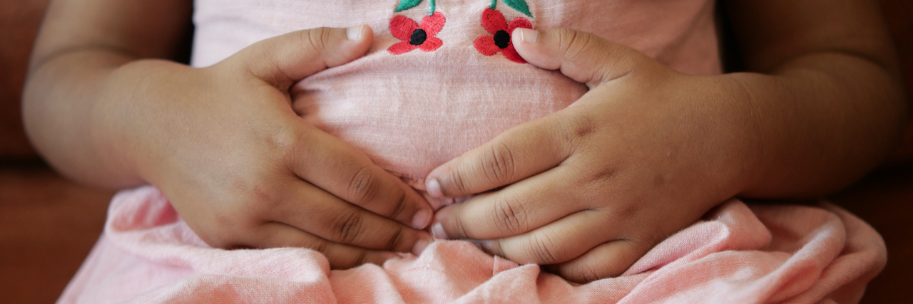 Child's hands holding their stomach