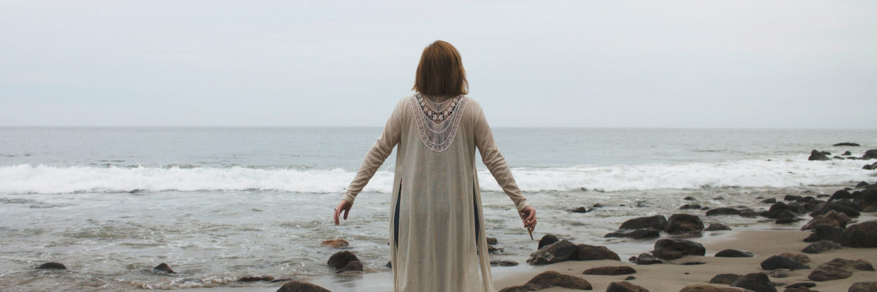 Rejection-Sensitive Dysphoria: When Rejection Hits You Harder With ADHD Woman standing with arms open on a beach, looking out at the water