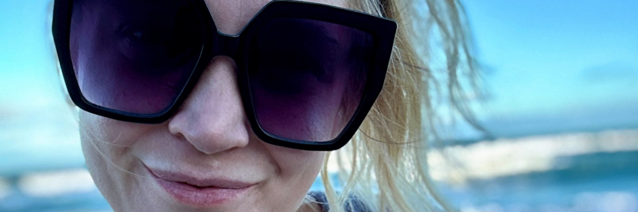 5 Ways Emotional Invalidation Impacts Trauma Contributor, a woman with blonde hair wearing sunglasses, outside with sunset behind her