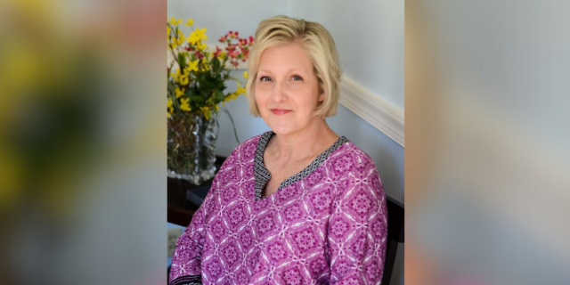 It's Time to Put Patients Over Profit Contributor seated at home with flowers behind her