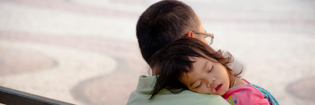 child sleeping on dad on a bench