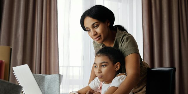 mom helping daughter with homework on computer