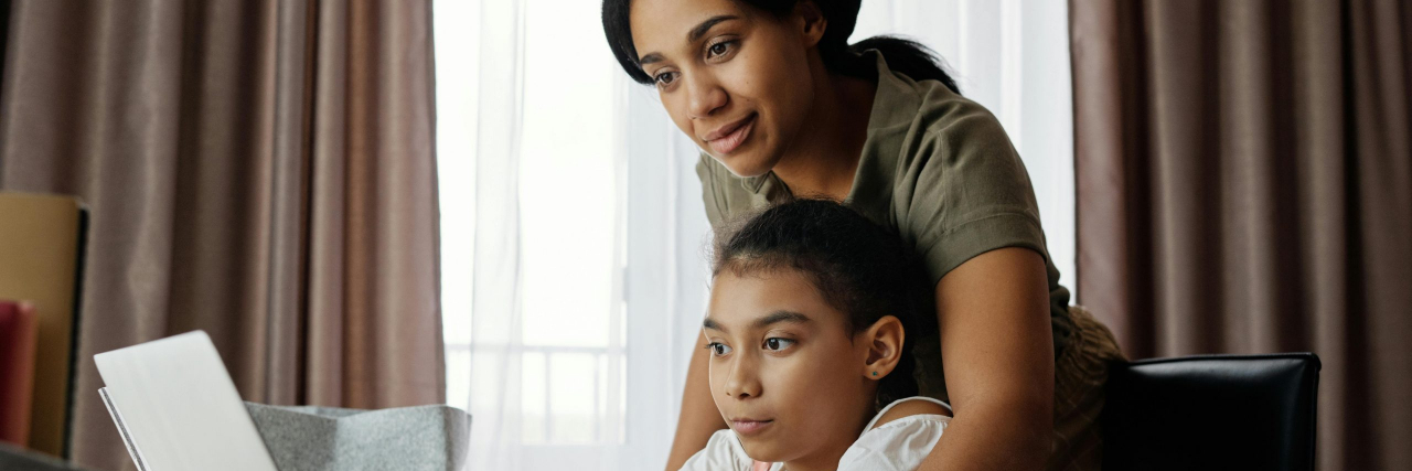 mom helping daughter with homework on computer