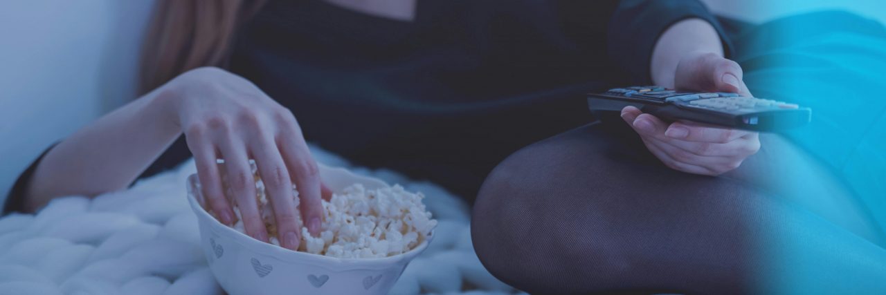 person watching tv in bed with popcorn