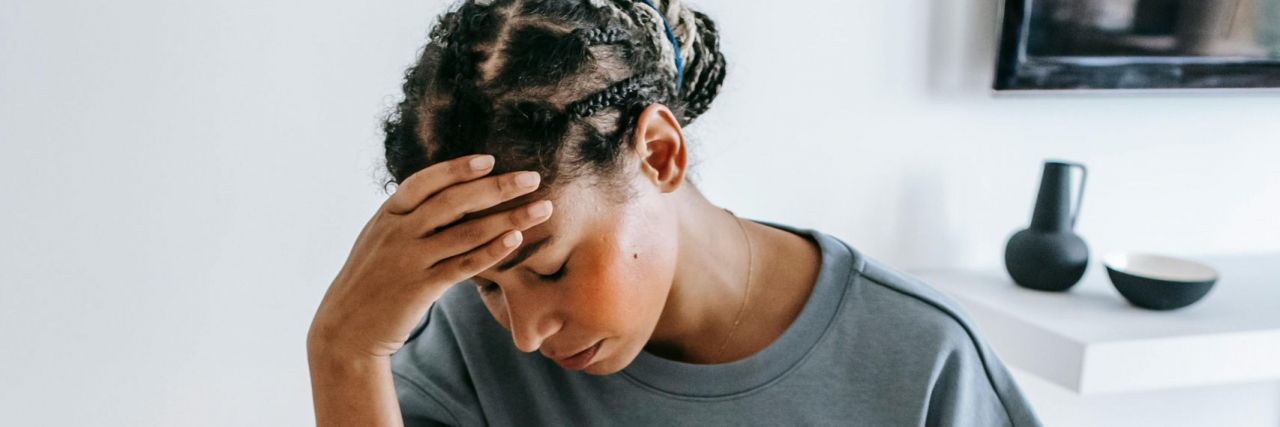 Confusing Migraine Symptoms: The Signs That Don’t Feel Like Migraines woman with migraine at her kitchen table