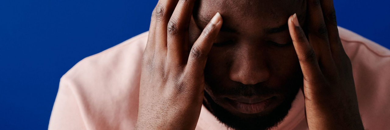 person with headache against bright blue wall