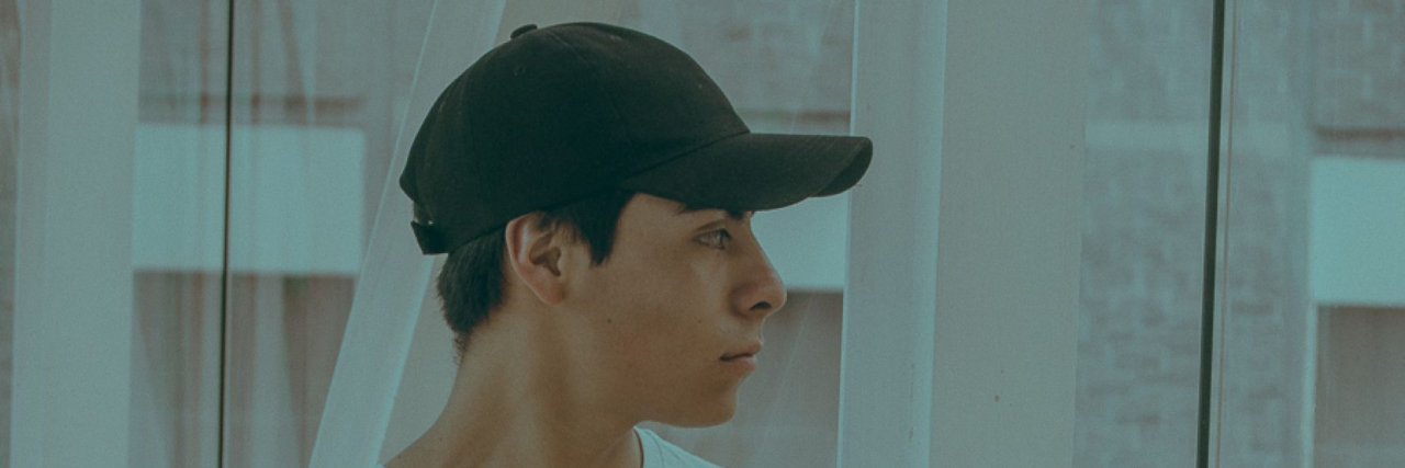 person looking out the window. wearing a hat.