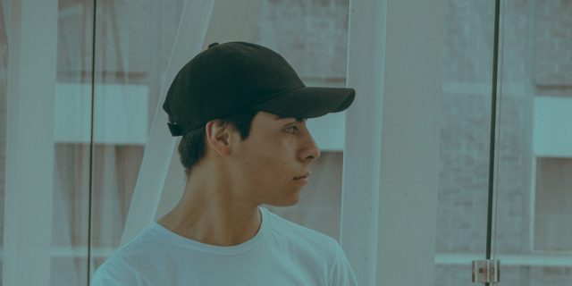 Signs of Aphantasia person looking out the window. wearing a hat.