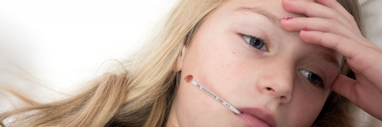 child with thermometer in mouth and headache