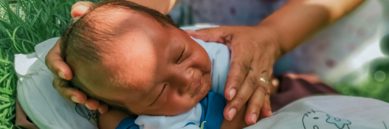 infant being held on the grass