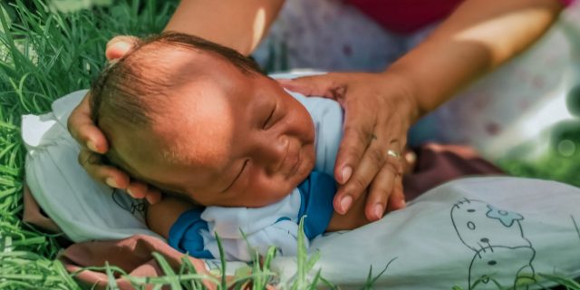 infant being held on the grass