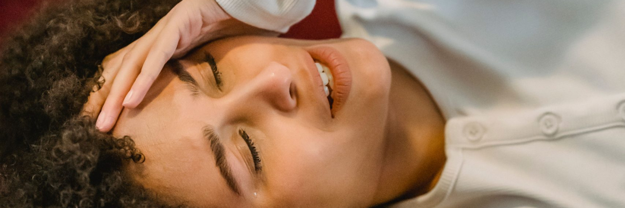 New Device Claims to Predict Migraine Attacks With Over 90% Accuracy: What to Know person with migraine on red couch