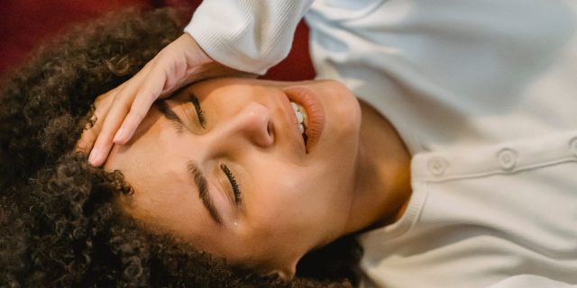 person with migraine on red couch